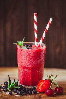 Front view of glass with fresh crimson smoothie with berries on wooden table. Healthy eating concept. Vitamin food. Selective focus 