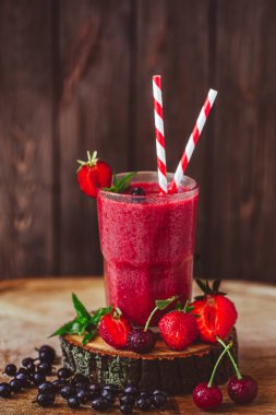 Composition of glass with fresh crimson smoothie with berries on wooden table. Healthy eating concept. Vitamin food. Selective focus 