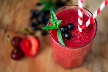 From above view of glass with fresh crimson smoothie with berries on wooden table. Healthy eating concept. Vitamin food. Selective focus 
