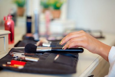 Selective focus, womans hand picking makeup brush. Makeup at home. Beauty concept 