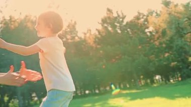 Happy little girl running on green grass in park to mother, then hugging her and kissing. Slow motion. 4k