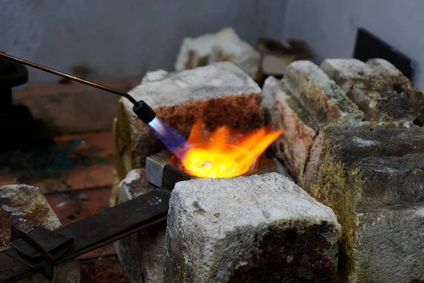 Flames are filling the crucible as silver is being melted down. Recycling of silver makes it sustainable