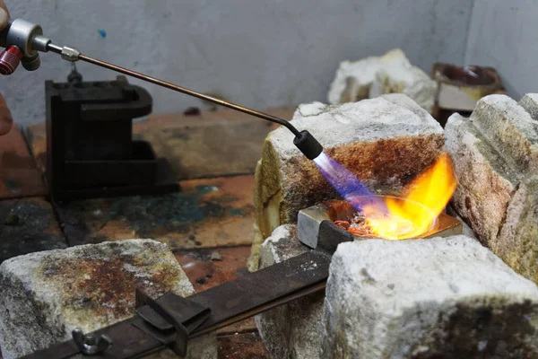 Flames burn brightly as heat is applied to a crucible full of unwanted silver, it is going to be melted down and used for casting