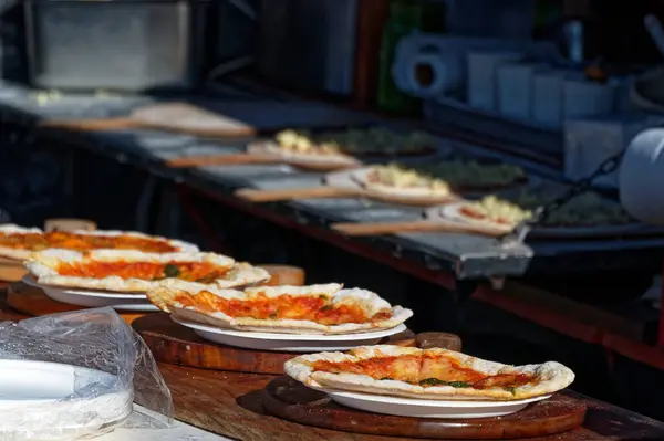Bazı pizzalar satılmaya hazır, diğerleri ise daha yeni hazırlanıyor.