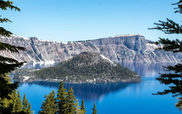 stock image Crater Lake in Oregon with snowy cliffsides and sunny conditions.