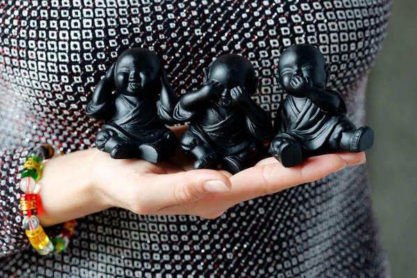 Woman with a set of 3 Baby Buddhist Monk Statues: See No Evil, Hear No Evil, Say No Evil. Close-up