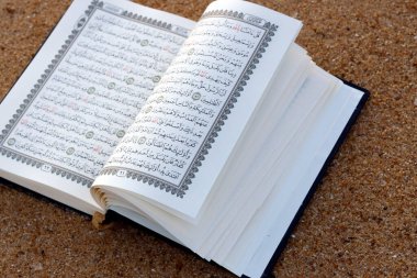 Open Quran on sand beach. 