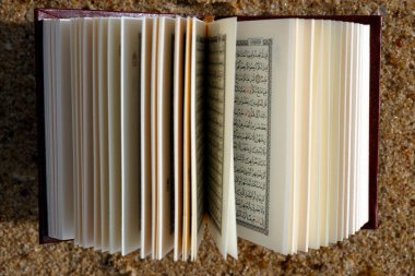 Open Quran on sand beach. Symbol of Islam. 