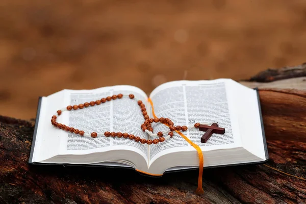 Wooden prayer beads and open Holy Bible on a trunk.