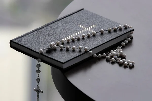 Bible with rosary on a table.  Religious symbol.
