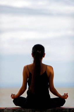 Denizin önünde nilüfer yogası pozisyonunda meditasyon yapan kadın silueti. Kep. Kamboçya. 