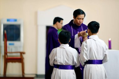 Katolik ayini. Kutsal komünyon. Rahip konukçuya veriyor. Quy Nhon. Vietnam. 