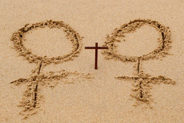 砂のビーチで書かれた女性の性別のシンボルとキリスト教の十字架 — ストック写真