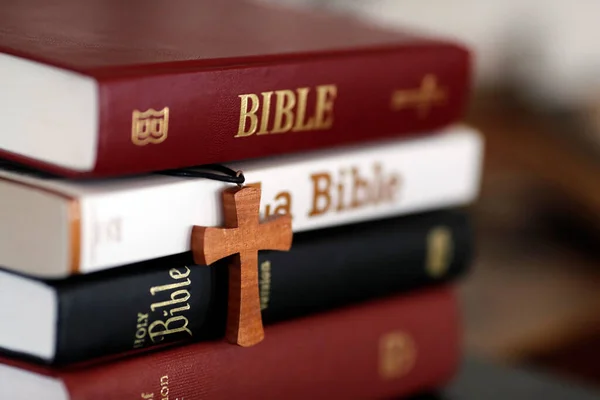 四个不同的圣经和一个基督教十字架放在桌子上 — 图库照片