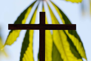 Gökyüzüne karşı ahşap haç ve yeşil yapraklar. Dini sembol.  
