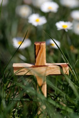Çimlerin üzerinde çiçeklerle ahşap haç. Dini sembol.