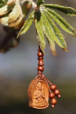 Ağaçtaki ahşap Buda kolyesi. Dini sembol.