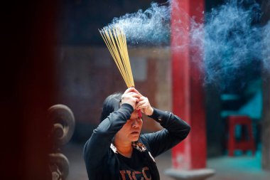 Taoist tapınağı. İmparator Jade pagoda (Chua Phuoc Hai). Taoist bir tapınmacı. Tütsü yakma çubukları. Ho Chi Minh Şehri. Vietnam. 