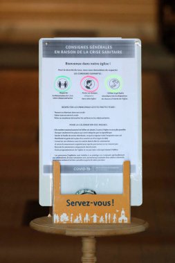 Coronavirus salgını sırasında kilise. COVID-19 talimatları: jel dezenfekte etme, cerrahi maske ve sosyal uzaklık. Fransa. 