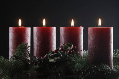 Dört yanan kırmızı mumlu doğal bir çelenk ya da taç. Noel kompozisyonu. 