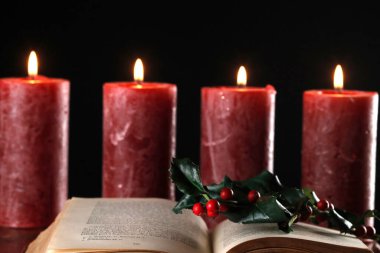 İncil 'i aç, kutsal dal ve dört yanan kırmızı mumla ortaya çıkan çelenk. Noel kompozisyonu.  