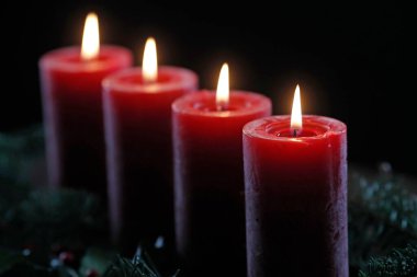 Dört yanan kırmızı mumlu doğal bir çelenk ya da taç. Noel kompozisyonu.