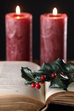 İncil 'i, kırmızı mumları ve Holly Branch' ı aç. Noel kompozisyonu. Fransa. 