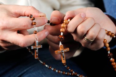 Katolik bir adam ve kadın evde birlikte dua ediyorlar. Dua boncuklarıyla ellerini kapat. Fransa. 