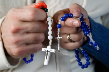 Catholic man and woman praying together at home. Close up on hands with prayer beads.   clipart