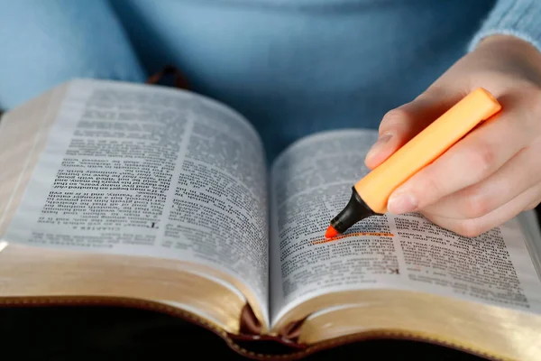 Woman studying the bible. Close up on hand and highlighter.   France.