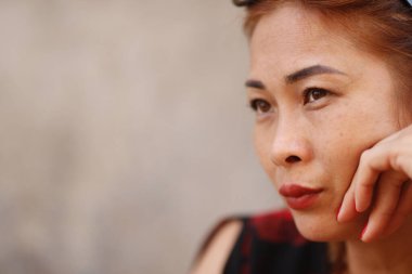 Asyalı bir kadının portresi. Düşünüyor, üzgün, başka tarafa bakıyor.. 