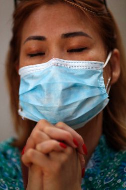 Koronavirüs salgını sırasında kilisede dua eden cerrahi maskeli bir kadın. Covid 19. 