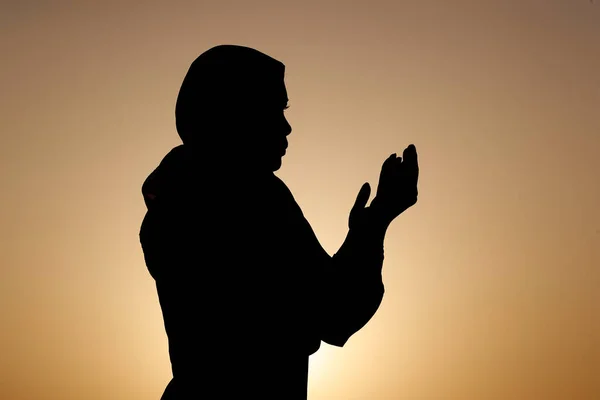 Gün Batımında Elleri Havada Dua Eden Müslüman Bir Kadının Silueti — Stok fotoğraf