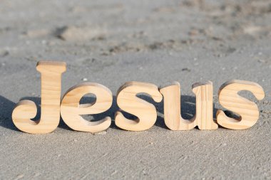 Sahildeki kumların üzerinde İsa kelimesini oluşturan tahta harfler. Hıristiyan sembolü.