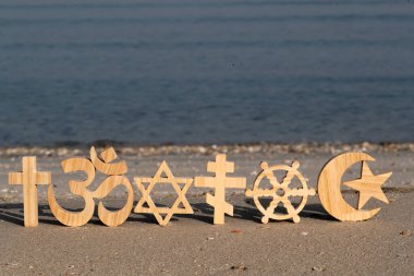 Kum üzerinde dini semboller. Hıristiyanlık, İslam, Yahudilik, Ortodoksluk Budizm ve Hinduizm. Dinlerarası ya da dinler arası kavram
