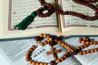 Hristiyanlık ve İslam dünyanın en büyük iki dinidir. İncil, Kuran. Haç ve tespih. Dinlerarası semboller.