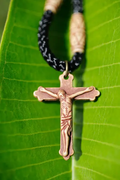 在新鲜的绿色木兰花叶上的基督教十字架特写镜头 信仰和灵性 — 图库照片