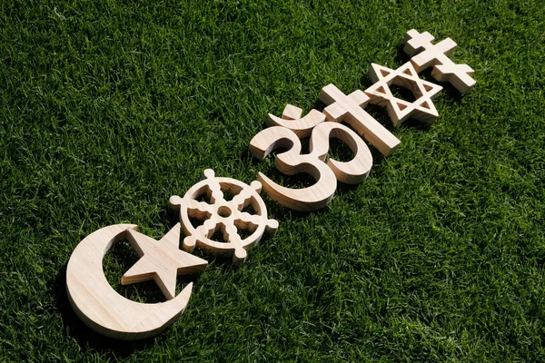 Religious symbols on grass. Christianity, Islam, Judaism, Orthodoxy Buddhism and Hinduism. Interreligious or interfaith concept