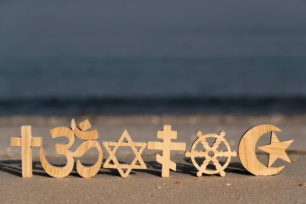 Religious symbols on sand. Christianity, Islam, Judaism, Orthodoxy Buddhism and Hinduism. Interreligious or interfaith concept