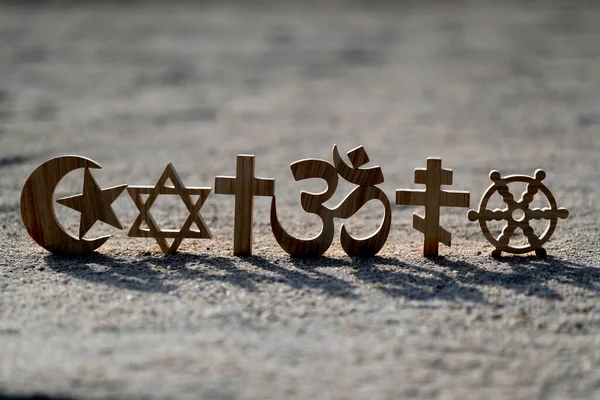 Religious symbols on sand. Christianity, Islam, Judaism, Orthodoxy Buddhism and Hinduism. Interreligious or interfaith concept