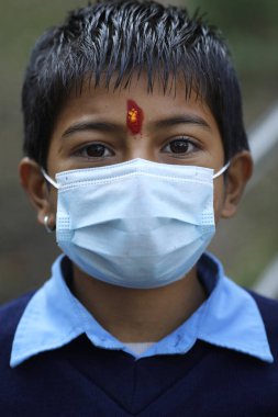 İlkokul. Covid-19 salgını sırasında cerrahi maske takan öğrenci portresi. Nepal. 