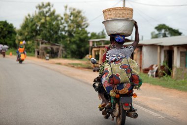 Motosiklet süren Afrikalı insanların olduğu sokak sahnesi. Benin.. 