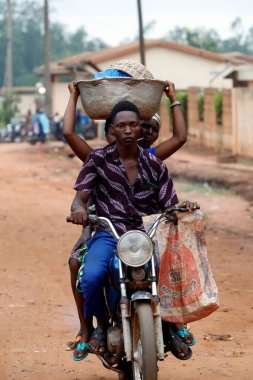 Motosiklet süren Afrikalı insanların olduğu sokak sahnesi. Benin.. 