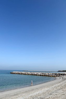 Al Hamra Sahili, Arap Körfezi, Ras Al Khaimah. Kumsalda yalnız yürüyen bir kadın. Birleşik Arap Emirlikleri.