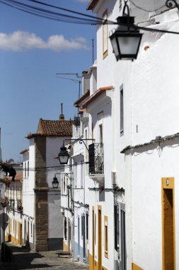 Taş sokak, tipik beyaz ve sarı evlerin yanında. Evora. Portekiz. 