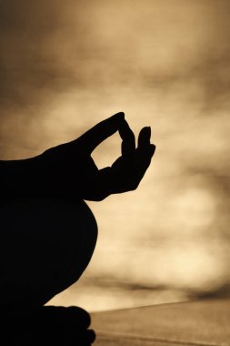 Nilüfer pozisyonunda meditasyon yapan genç bir kadının elini kapat. Gün batımında yoga.. 
