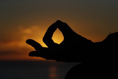Gün batımında, sessizlik ve rahatlama kavramı olarak deniz kenarında yoga meditasyonu yapan bir kadın. Yakın plan, Gyan Mudra.. 