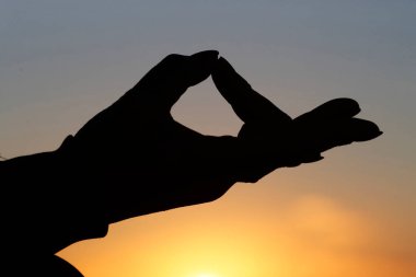 Gün batımında, sessizlik ve rahatlama kavramı olarak deniz kenarında yoga meditasyonu yapan bir kadın. Yakın plan, Gyan Mudra.. 