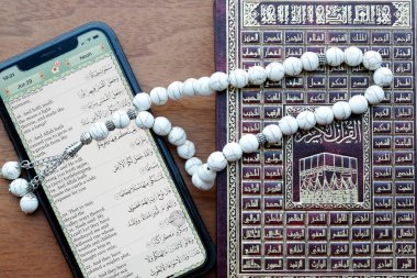 Tablet üzerinde dijital Kuran ve kağıt üzerinde geleneksel Kuran.. 