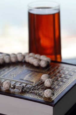 Arapça kutsal Kur 'an, müslüman tespihi, bir bardak çay. İslam sembolleri ve Ramazan Kareem kavramı. 